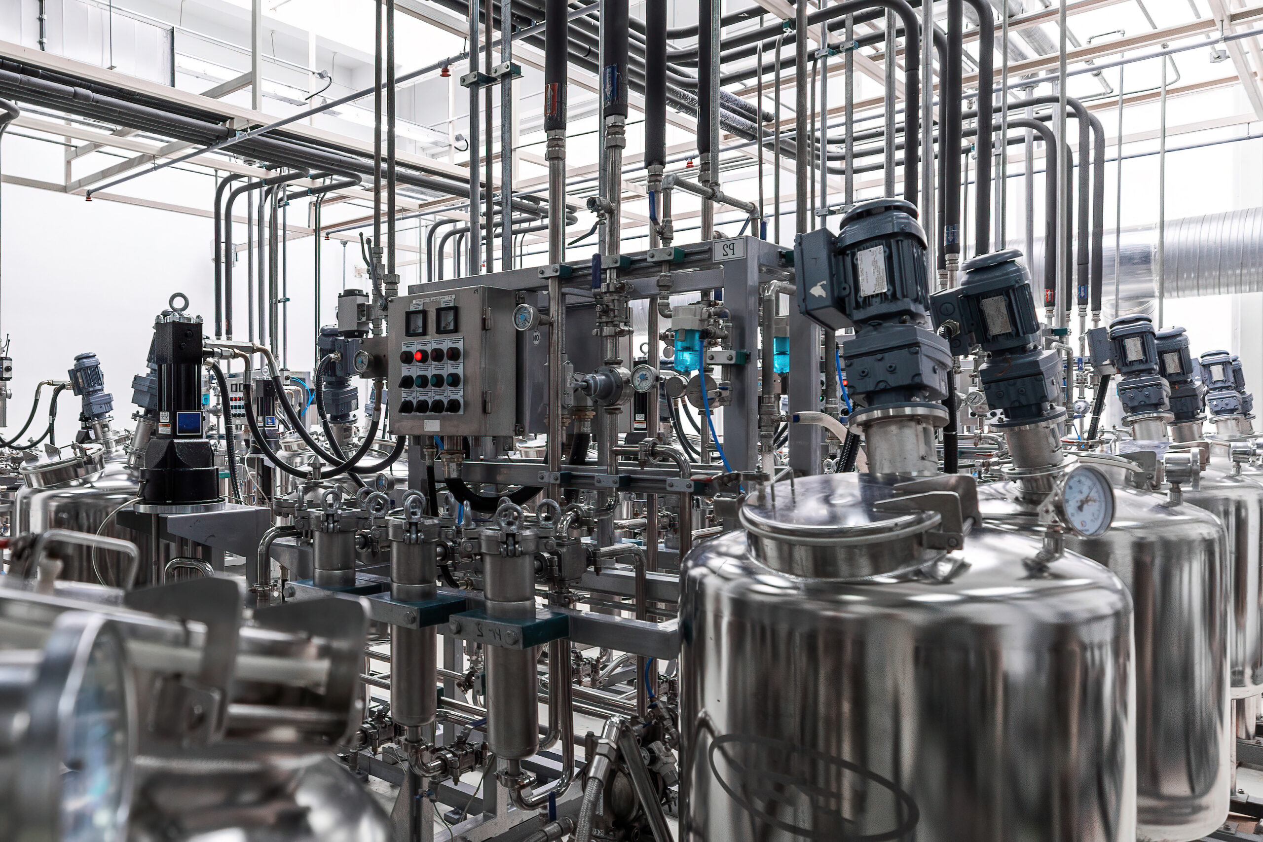 Interior of a high-tech industrial plant with stainless steel pipes and tanks